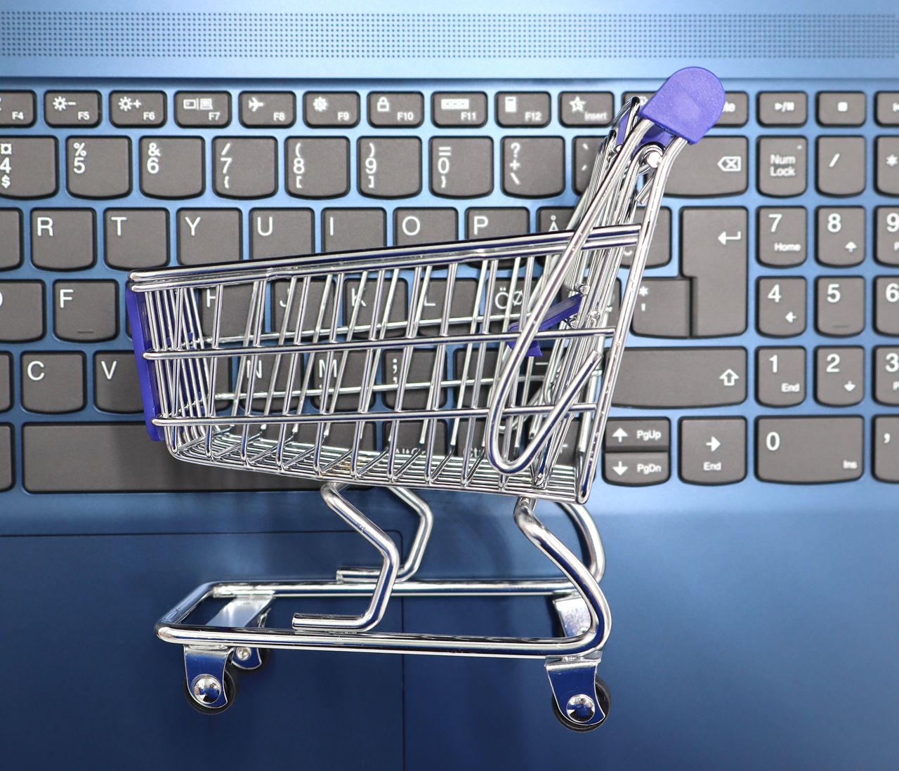 Une mini-panière d’achat posée sur le clavier d’un ordinateur portable, illustrant les achats en ligne et le commerce électronique.